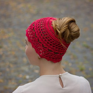 May include: A red crocheted headband with a lacy design. The headband is worn by a person with their hair pulled back in a bun.