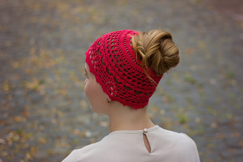 May include: A red crocheted headband with a lacy design. The headband is worn by a person with their hair pulled back in a bun.