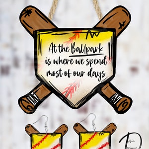 May include: A set of baseball-themed earrings and a sign. The earrings feature a yellow and white baseball with red stitching, crossed wooden bats, and a home plate. The sign has the same design and the text "At the Ballpark is where we spend most of our days".