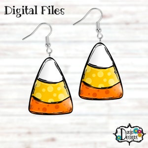 May include: A pair of dangle earrings featuring a candy corn design. The candy corn is yellow, orange, and white with black outlines and polka dots. The earrings are silver.