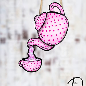May include: A pink teapot with white polka dots pours tea into a pink teacup with white polka dots. The teapot and teacup are hanging from a string.