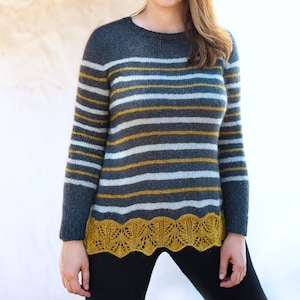 May include: A striped sweater with a grey, white, and yellow color scheme. The sweater has a lace trim at the bottom.