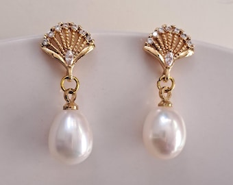 May include: A pair of gold earrings with a pearl drop and a fan-shaped design with clear rhinestones.