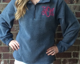 May include: A gray fleece pullover with a quarter zip closure and a pink monogram "JOM" embroidered on the chest.