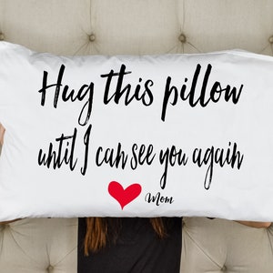 May include: White pillow with black text that reads "Hug this pillow until I can see you again" with a red heart and the word "Mom" below it.