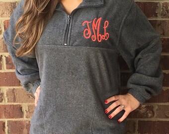 May include: A gray fleece pullover with a quarter zip closure and a red embroidered monogram "JML" on the chest.