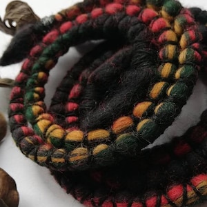 May include: A pair of black, green, red, and yellow braided wool bracelets. The bracelets are coiled and have a woven design.