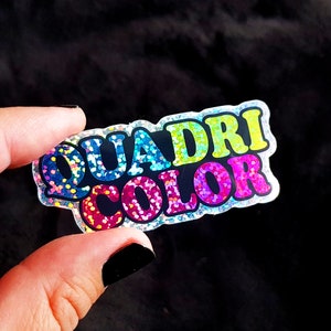 May include: A sparkly rainbow sticker with the text "QUADRI COLOR" in black letters.