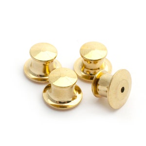 Peut inclure: Quatre dos de broche en métal de couleur dorée. Les dos de broche sont ronds avec un petit trou au centre.