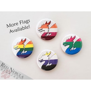 May include: Four round button pins with a white background and a dragon silhouette in the center. Each dragon is outlined in black and has a different pride flag design. The flags are rainbow, lesbian, bisexual, and transgender.