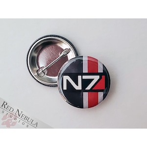 May include: A black and white button with a red and white stripe design. The button features the text "N7" in white.