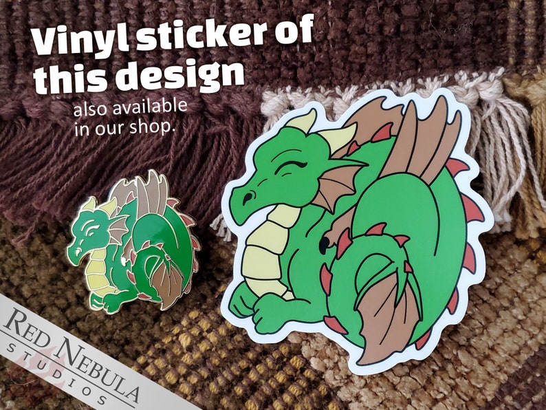 May include: A green dragon sticker and pin with brown and red accents. The sticker and pin feature the text "Vinyl sticker of this design also available in our shop."