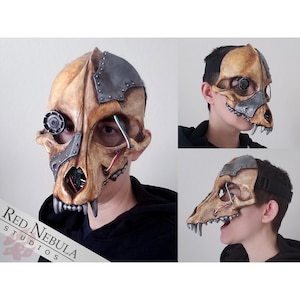 May include: A beige and silver steampunk-style animal skull mask with a gear eye and metal accents. The mask is worn by a person, and the image shows the mask from the front, side, and profile views.