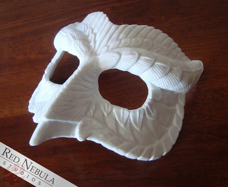May include: White owl mask with detailed feather design. The mask has a single eye hole and a beak-like nose.