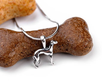 Puede incluir: Collar con colgante de perro galgo plateado en una cadena plateada, descansando sobre dos golosinas en forma de hueso de perro marrón.