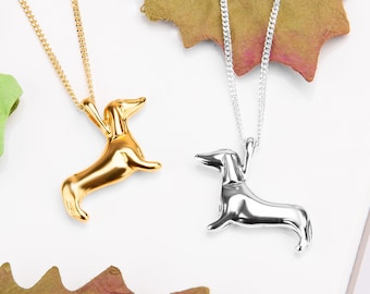 May include: Two silver necklaces with dachshund pendants. One necklace has a gold dachshund pendant.