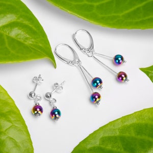 Può includere: Un set di orecchini iridescenti con perni e ganci in argento. Gli orecchini presentano perle rotonde color arcobaleno.
