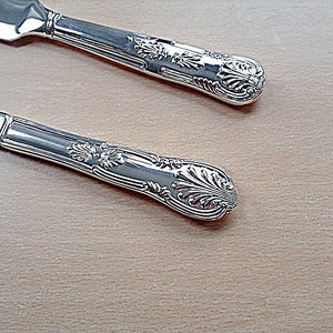 May include: Two silver cake servers with ornate handles. The servers have a decorative, floral design.