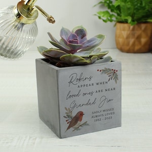 May include: A gray concrete planter with a succulent plant. The planter has a robin design and the text "Robins appear when loved ones are near Grandad Jim Sadly missed Always loved 1952 - 2023".