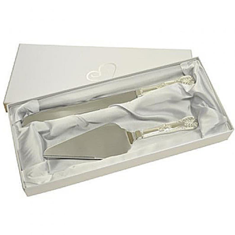 May include: A white box with a silver cake knife and server set inside. The set is wrapped in white tissue paper.