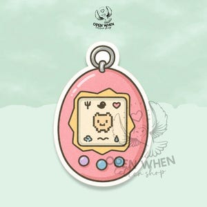 May include: A pink, egg-shaped sticker featuring a pixelated pet game design. The screen displays a small, smiling character with icons of a heart, bird, and water droplet. The sticker has a silver ring at the top and three colored buttons at the bottom.