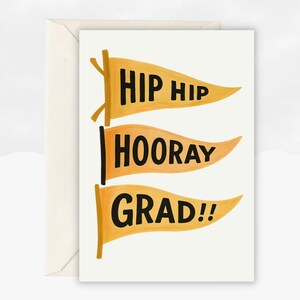 May include: A graduation card featuring three orange pennant flags with black text. The flags display the phrases "HIP HIP", "HOORAY", and "GRAD!!". The card is presented inside a cream envelope.