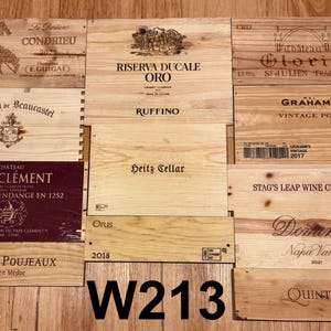 May include: A collection of wooden wine crate lids with various winery names and logos. The lids are made of light-colored wood and feature text and graphics in dark ink. The text "W213" is visible in the image.