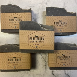 Puede incluir: Cinco barras de jabón de carbón negro con una etiqueta marrón que dice "CHAUTAUQUA SOAP CO. NATURAL HANDMADE SOAP SUB-ZERO *"