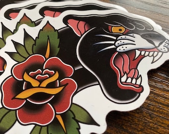 May include: A black panther with a snarling expression, a red rose with yellow center, and green leaves. The image is in a traditional tattoo style.