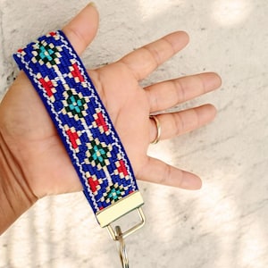 May include: A blue and red patterned key chain with a gold metal ring and a gold metal clasp.