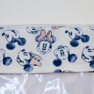 May include: A white zippered pouch with a clear plastic front. The pouch has a white fabric lining with a repeating pattern of blue and pink Mickey Mouse and Minnie Mouse heads.