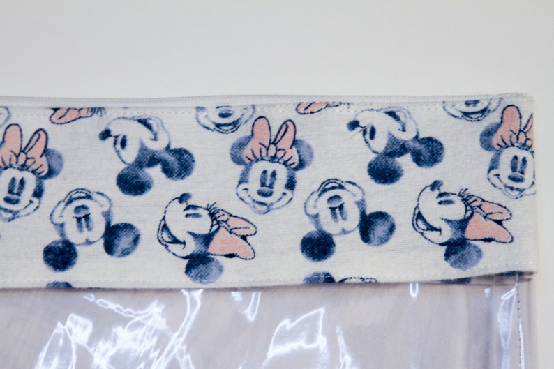 May include: A white zippered pouch with a clear plastic front. The pouch has a white fabric lining with a repeating pattern of blue and pink Mickey Mouse and Minnie Mouse heads.
