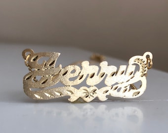 May include: Gold nameplate necklace with the name "Jerald" cut out in a cursive font.