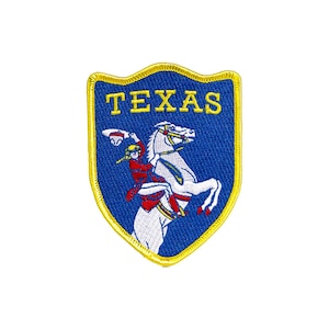 Peut inclure: Un écusson brodé bleu et jaune avec le mot "TEXAS" en lettres jaunes. Un cheval blanc avec un cavalier en vêtements rouge et blanc est représenté sur l'écusson.
