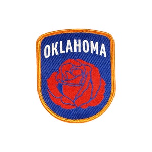 May include: A blue and orange embroidered patch with the word "OKLAHOMA" in white lettering and a red rose in the center.
