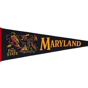 May include: A black felt pennant with yellow fringe and red trim. The pennant features a yellow silhouette of the state of Maryland with the words "The Free State" and a depiction of a bird, a ship, and a cannon. The word "MARYLAND" is printed in yellow across the pennant.