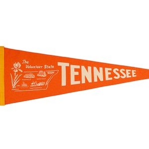 May include: Orange felt pennant with white text that reads "The Volunteer State TENNESSEE". The pennant features a white outline of the state of Tennessee with small illustrations of cities and landmarks.