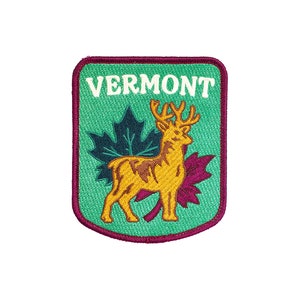 May include: An embroidered patch in green and burgundy with a white outline. The patch features a deer with antlers standing in front of a maple leaf. The text "VERMONT" is printed in white at the top of the patch.