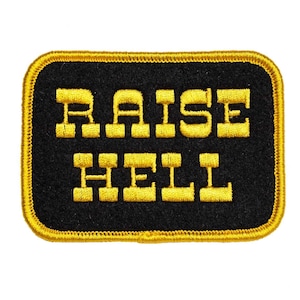 May include: A black and gold embroidered patch with the text "RAISE HELL" in yellow.