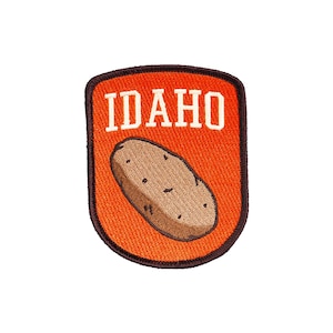 May include: Orange embroidered patch with a brown potato and the word "IDAHO" in white text.