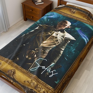 May include: A decorative blanket featuring a character in ornate armor against a blue and green background. The blanket has a gold-colored frame design and the word "Sofas" in white script.