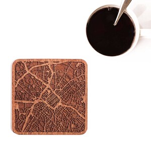 May include: A wooden coaster featuring a detailed laser-engraved map of a city. The coaster is brown and has a square shape.