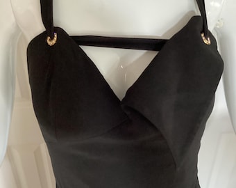 May include: A black halter-style dress with a deep V-neckline and a gold accent at the straps.
