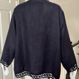 May include: Navy blue jacket with long sleeves and a decorative trim along the cuffs and hem. The trim features a geometric openwork design. The jacket is displayed on a mannequin.
