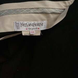 Puede incluir: Una etiqueta blanca con texto negro que dice "Yves Saint Laurent rive gauche" y "Made in France" con una etiqueta de talla 38.