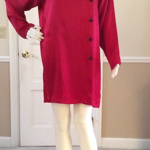 May include: A long-sleeved, red, satin tunic dress with a high collar and a row of black buttons down the side.