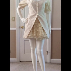 May include: A white dress with a lace skirt and a button-up bodice. The dress has short sleeves and a scoop neckline.