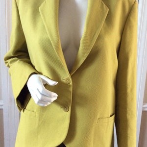 Può includere: Un blazer giallo con chiusura a due bottoni e una tasca sul lato sinistro.