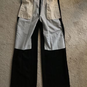 Puede incluir: Pantal&oacute;n negro con una cintura blanca y dos grandes bolsillos blancos en la parte posterior.