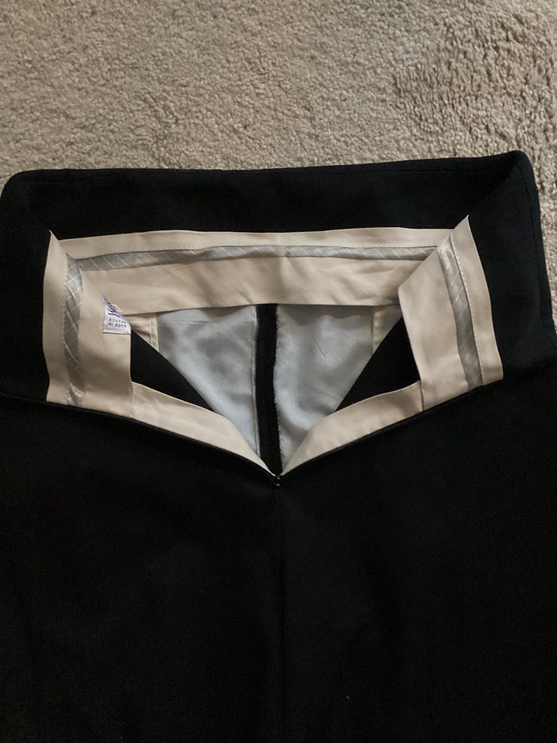 Puede incluir: Pantal&oacute;n negro con cintura blanca y una banda plateada. La cintura tiene una etiqueta blanca con texto negro.